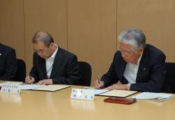 協定書にサインをする板川市長（写真右）と佐藤学長（写真左）