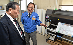 布川社長(右)から印刷機の説明を受ける高橋市長(左)