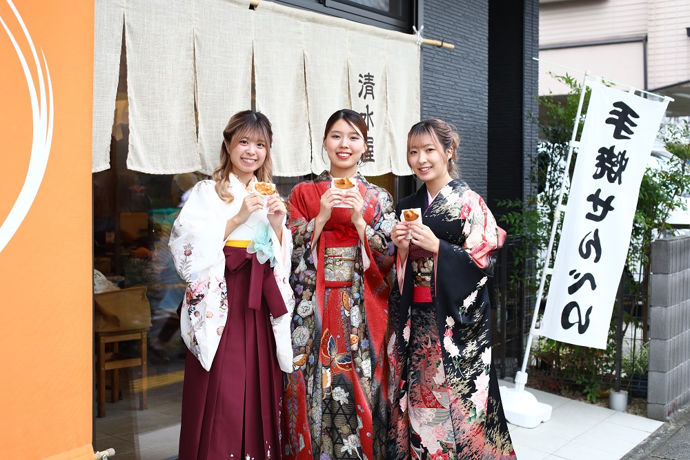 ナビゲーターである越谷市役所プロモーションZ係の3人の女性がせんべいを持っている写真